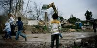 A boy watches an excavator destroy homes during the Casilino 900 forced eviction, Italy, 2009.  © Christian Minelli